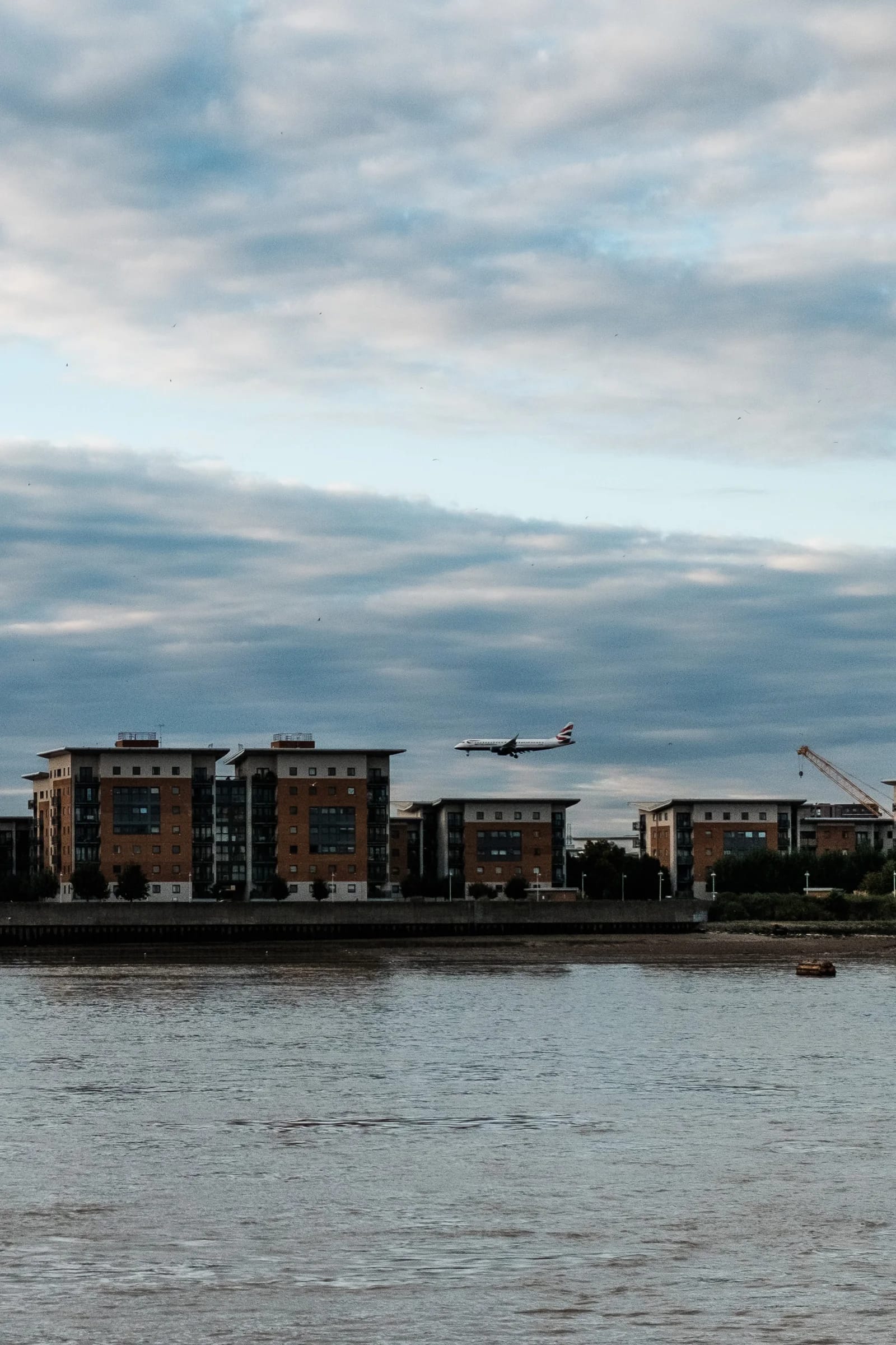 Plane flies over riverfront apartment buildings