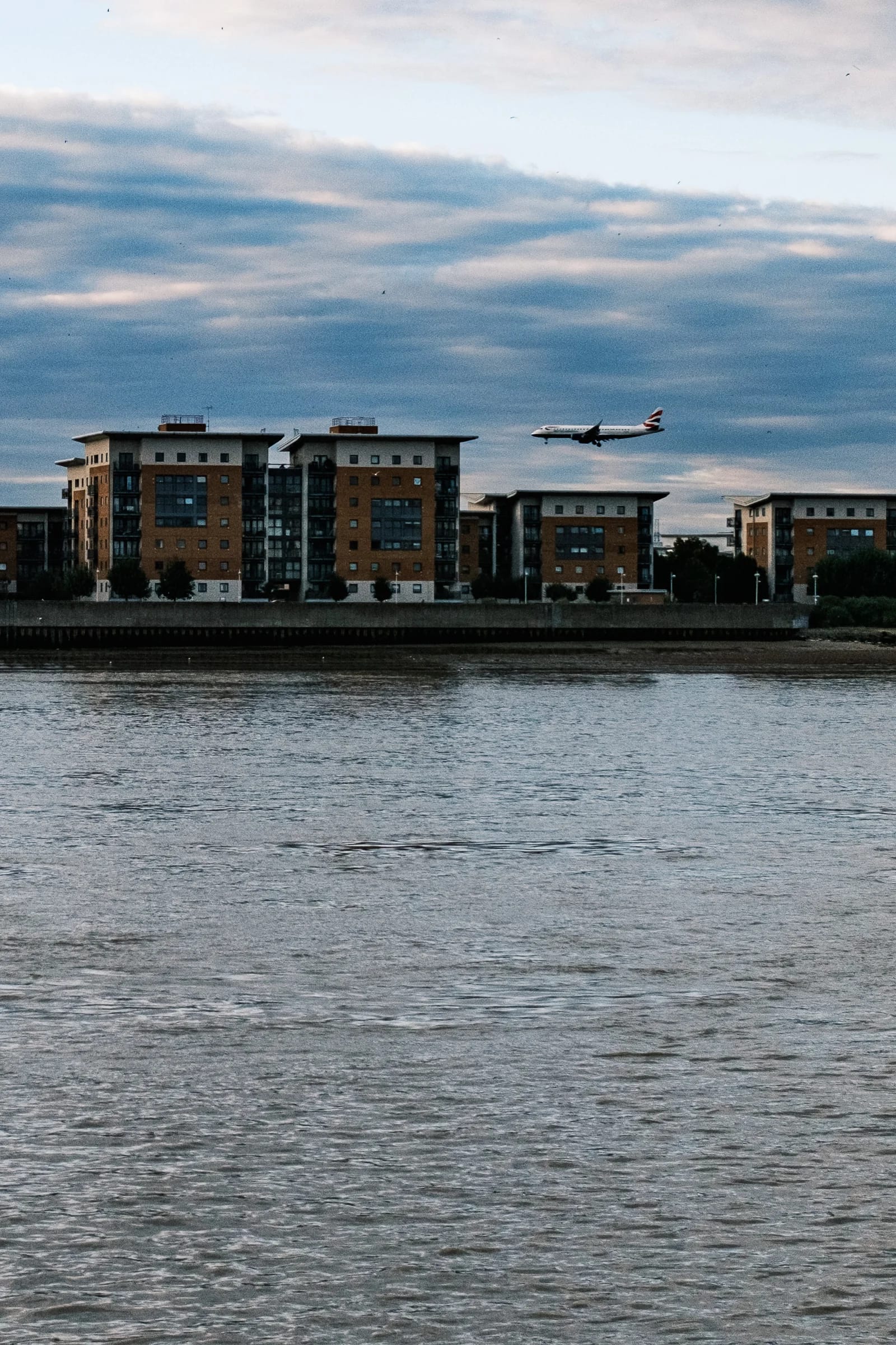 Airplane Flying Over Riverside Apartments